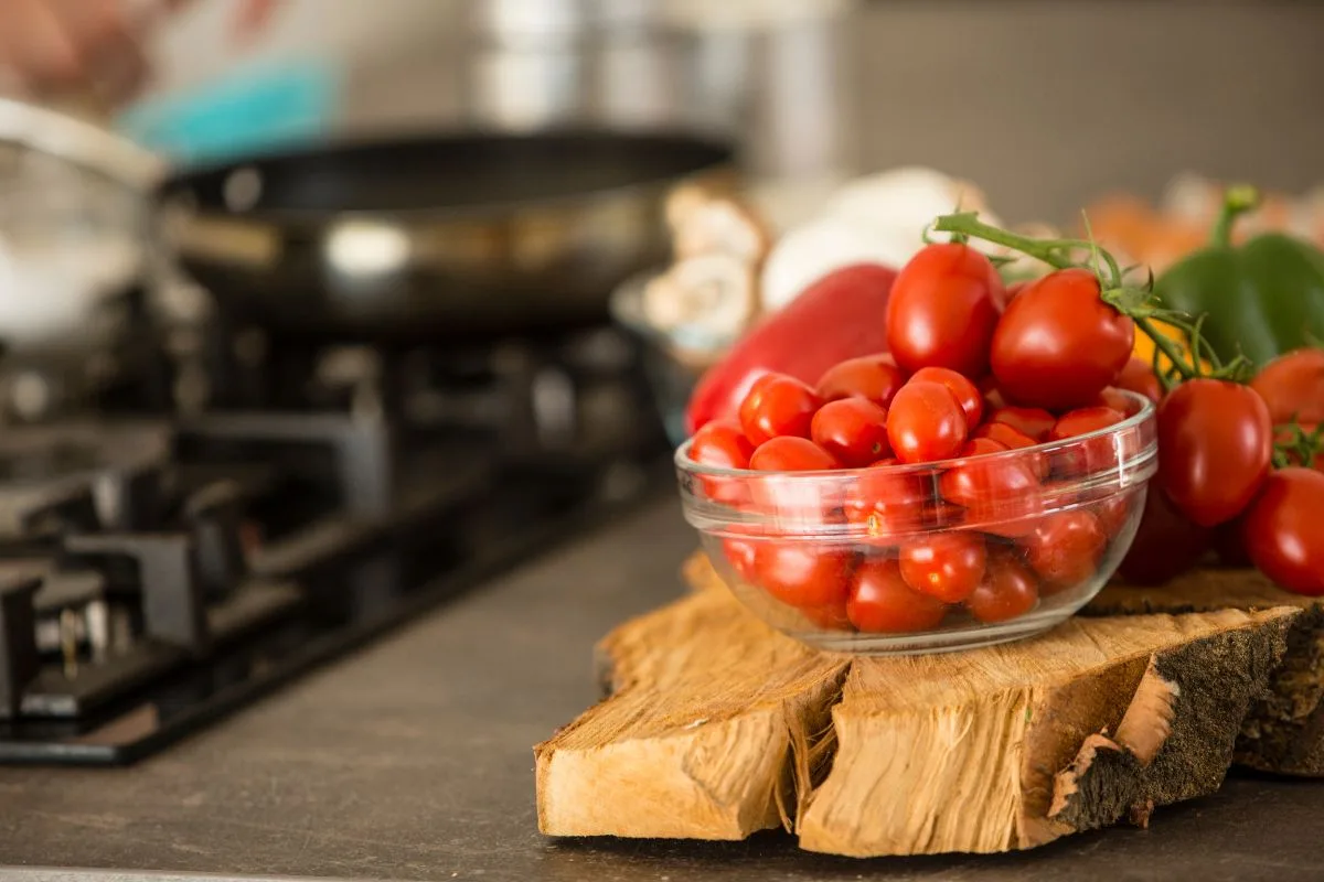 types of food that shouldn't be refrigerated including fresh tomatoes on a wooden cutting board